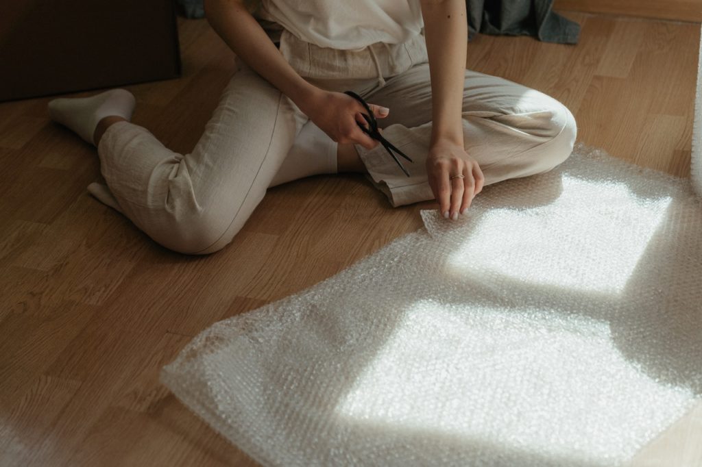A person using bubble wrap to pack their belongings before using self-storage