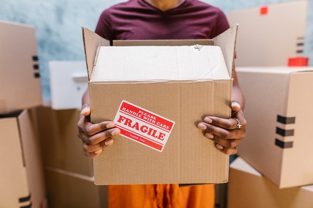 a person holding a moving box with fragile items