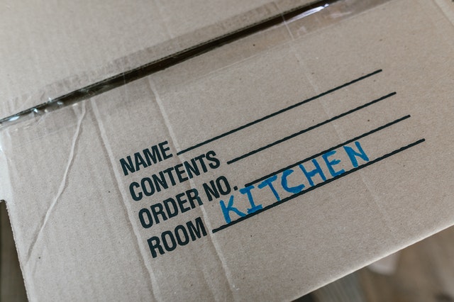a box labeled kitchen, representing one of the things to do when you need to pack and move on short notice