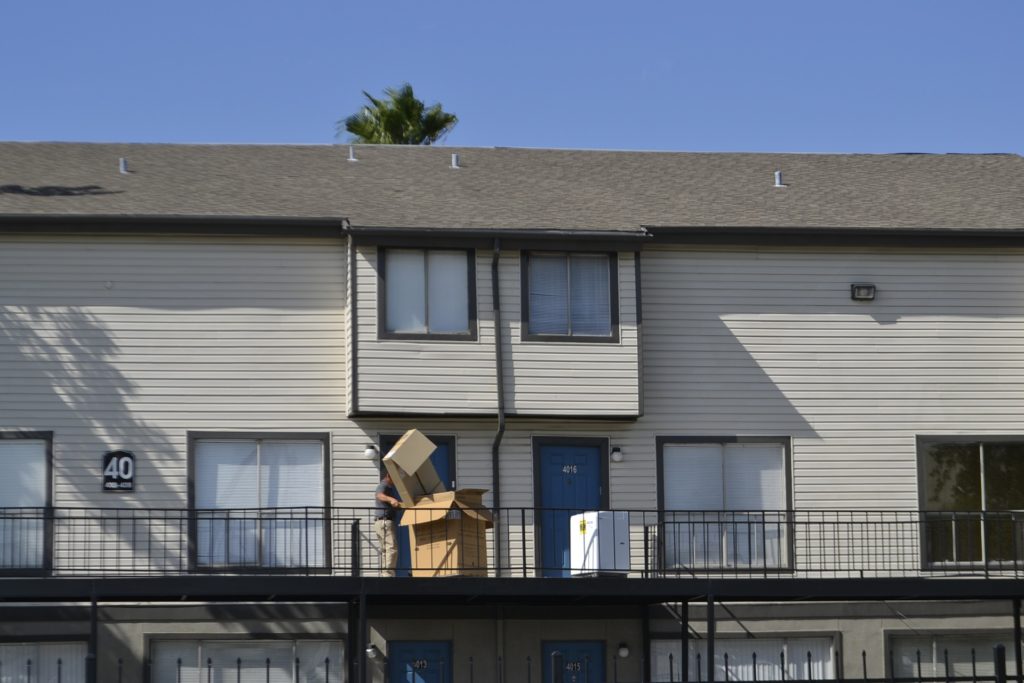 A view of a man carrying big cardboard boxes from home.