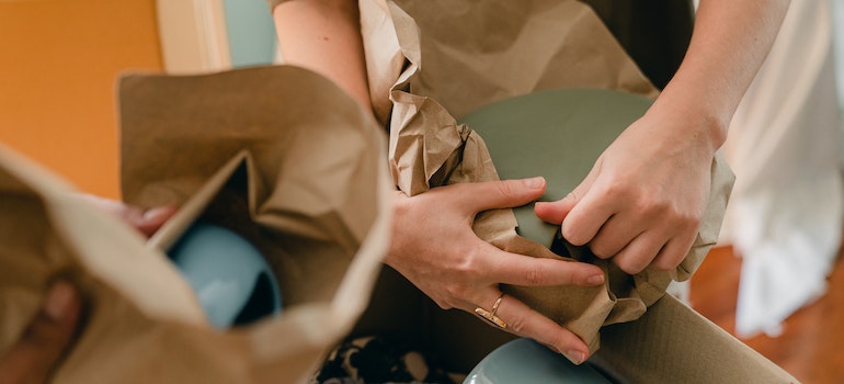 two people wrapping dishes in brown paper following the moving tips for Atlanta seniors