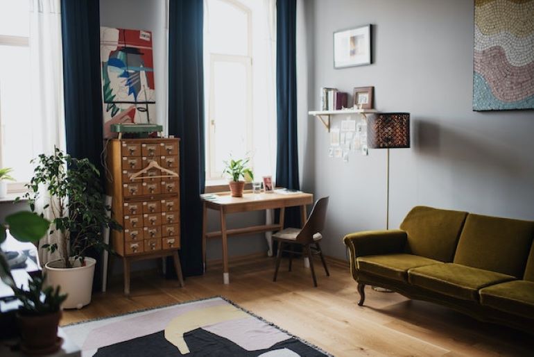 A room with a sofa, a chair, a desk, and a chest of drawers.
